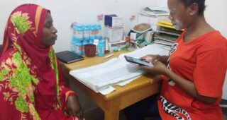 Community Health Worker using mobile app to assist patient at Tanzania health facility.
